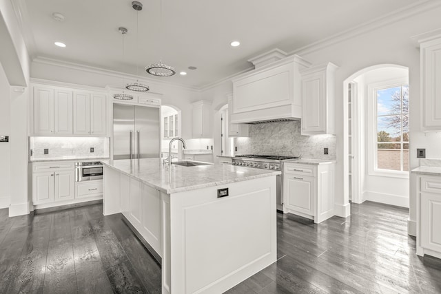 kitchen featuring white cabinetry, high end appliances, sink, and an island with sink