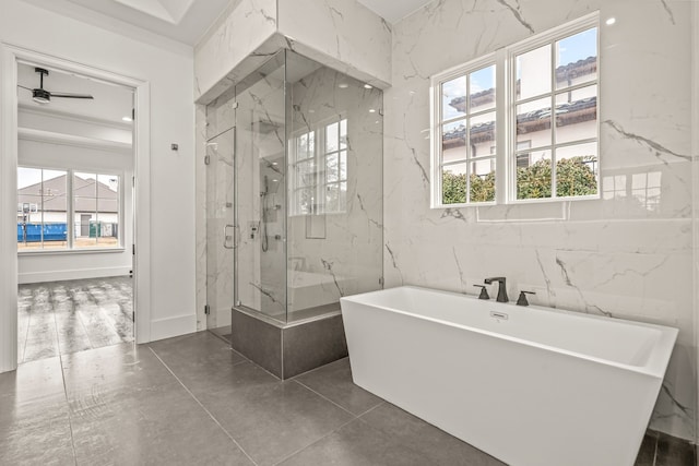 bathroom with tile walls, a wealth of natural light, and separate shower and tub