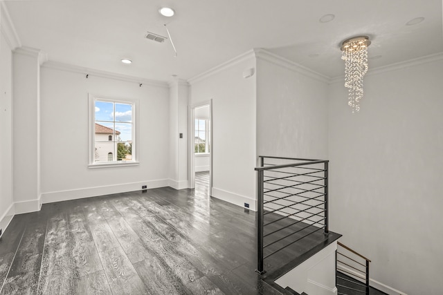 spare room with crown molding, dark hardwood / wood-style flooring, and a chandelier