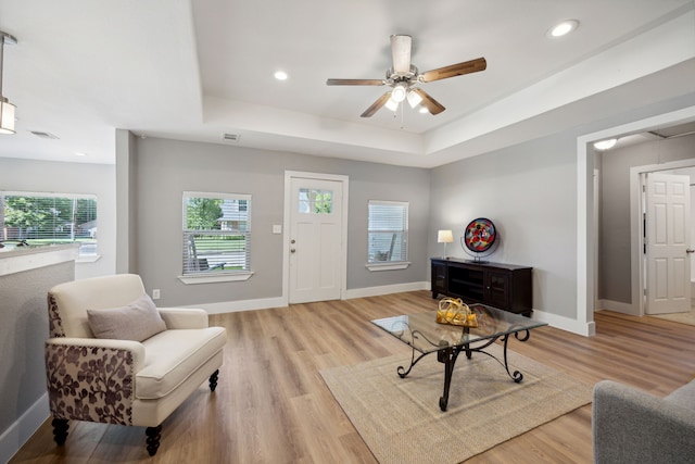 interior space with a tray ceiling, light hardwood / wood-style floors, and ceiling fan