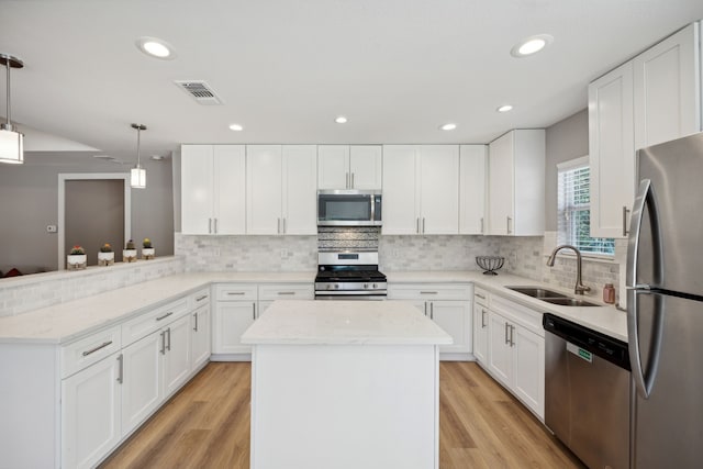 kitchen featuring stainless steel appliances, white cabinetry, pendant lighting, and kitchen peninsula