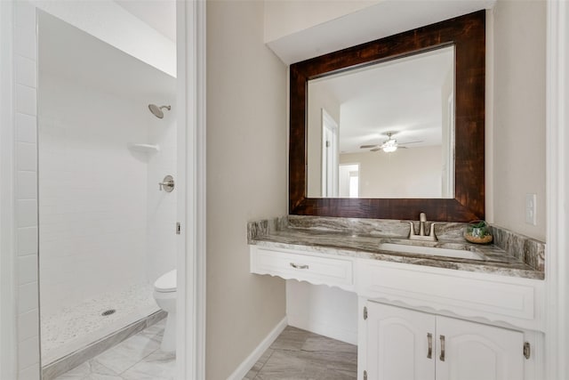 bathroom featuring ceiling fan, vanity, toilet, and a tile shower