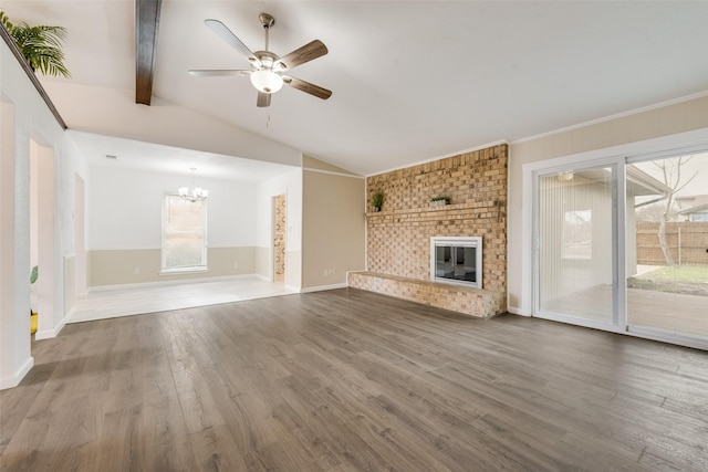 unfurnished living room featuring vaulted ceiling with beams, ceiling fan with notable chandelier, a fireplace, wood finished floors, and baseboards