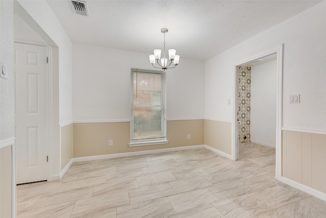 spare room with an inviting chandelier and a textured ceiling