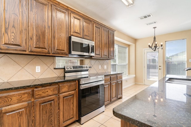 kitchen with tasteful backsplash, appliances with stainless steel finishes, sink, and dark stone countertops