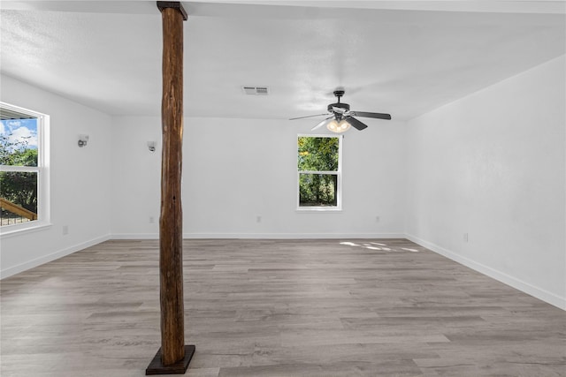 empty room featuring ceiling fan, a healthy amount of sunlight, and light hardwood / wood-style flooring