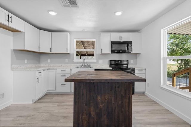 kitchen featuring white cabinetry, butcher block counters, sink, and black appliances