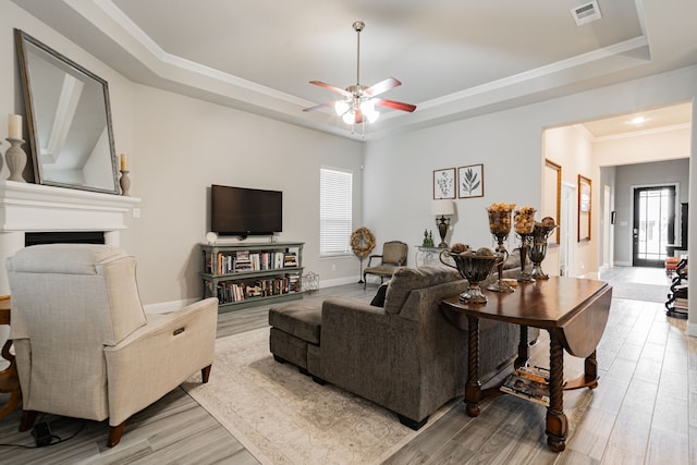 living room with crown molding, a tray ceiling, and light hardwood / wood-style flooring