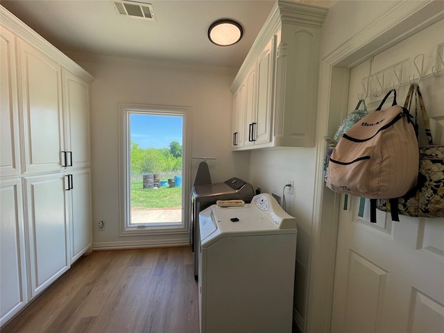 washroom featuring cabinets, washing machine and dryer, and light hardwood / wood-style flooring