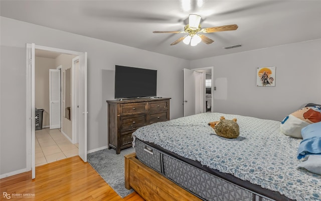 bedroom featuring a ceiling fan, visible vents, baseboards, and wood finished floors