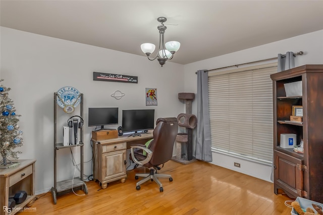 office area with light wood-style floors and an inviting chandelier