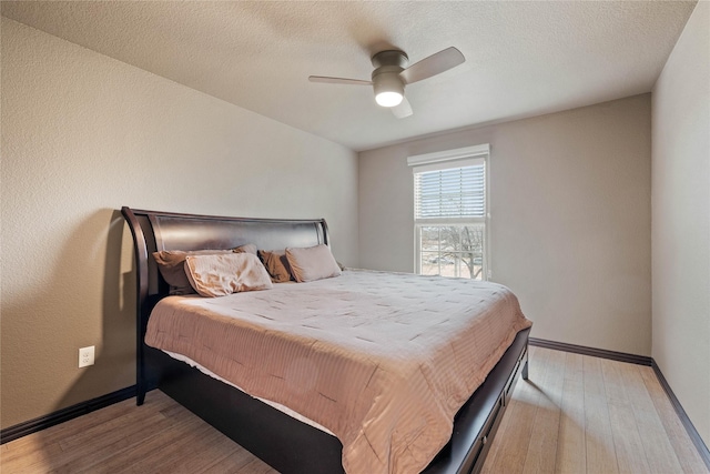 bedroom with ceiling fan, a textured ceiling, and light wood-type flooring