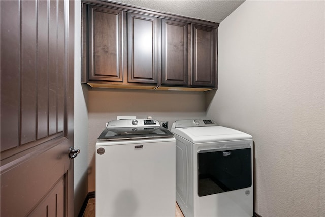 laundry area with cabinets, a textured ceiling, and independent washer and dryer