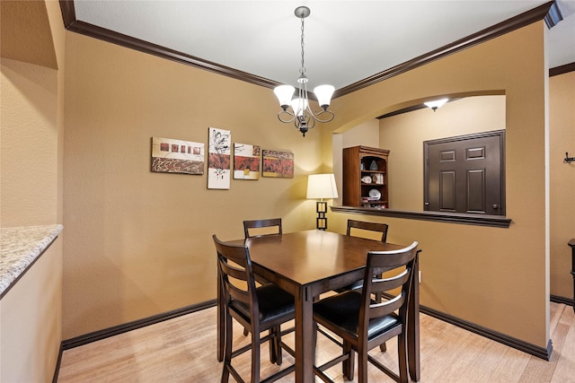 dining space with crown molding, a notable chandelier, and light wood-type flooring