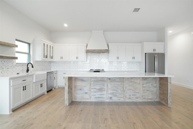 kitchen featuring stainless steel appliances, custom exhaust hood, a center island, and white cabinets