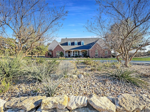 cape cod home featuring brick siding