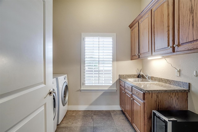 clothes washing area featuring cabinet space, a sink, baseboards, washer and dryer, and a wealth of natural light