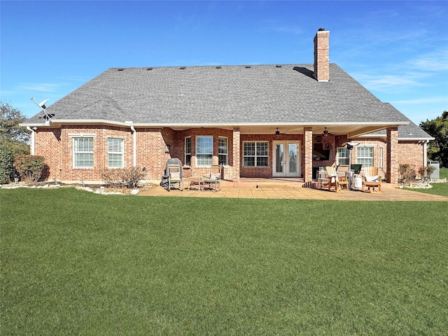 back of house featuring a lawn, a ceiling fan, french doors, and brick siding