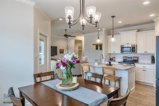 dining room featuring ceiling fan, light hardwood / wood-style flooring, crown molding, and sink