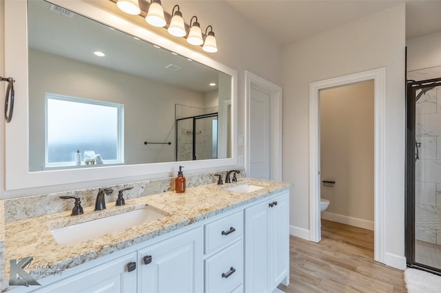 bathroom featuring vanity, wood-type flooring, a shower with shower door, and toilet