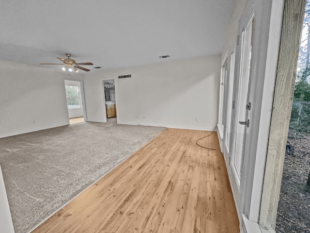 unfurnished living room featuring ceiling fan and light carpet