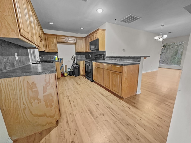 kitchen with hanging light fixtures, light hardwood / wood-style flooring, black appliances, and decorative backsplash