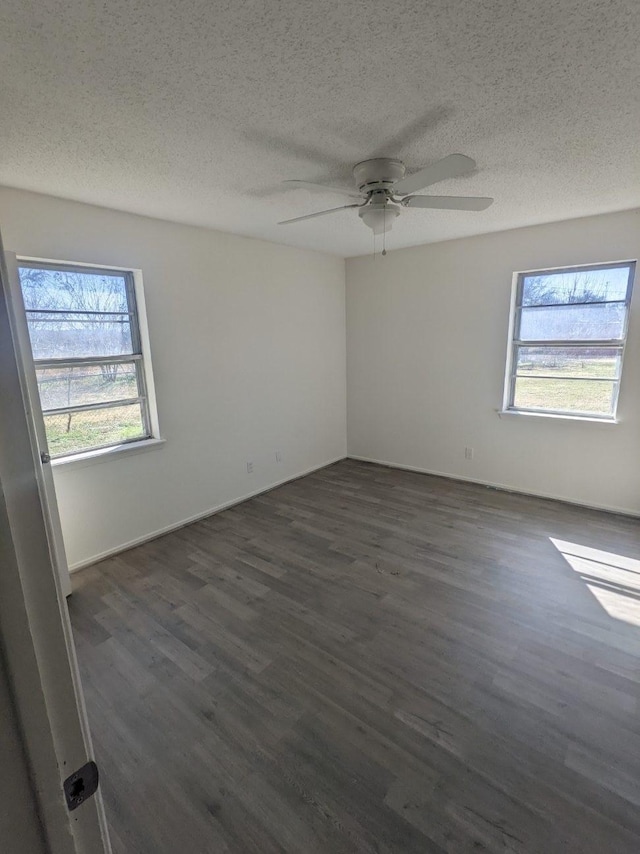 unfurnished room featuring a textured ceiling, dark wood-type flooring, and a healthy amount of sunlight