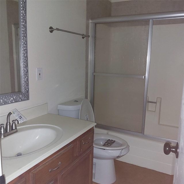 full bathroom featuring vanity, combined bath / shower with glass door, and toilet