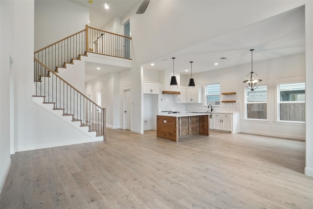 kitchen featuring premium range hood, pendant lighting, white cabinets, a center island, and light wood-type flooring