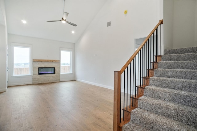 unfurnished living room with high vaulted ceiling, light hardwood / wood-style floors, and ceiling fan