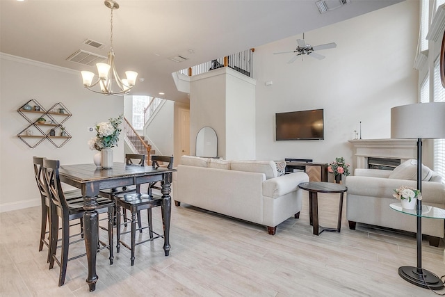 dining room with crown molding, a healthy amount of sunlight, ceiling fan with notable chandelier, and light hardwood / wood-style flooring