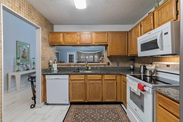 kitchen featuring sink, tasteful backsplash, a textured ceiling, dark stone countertops, and white appliances