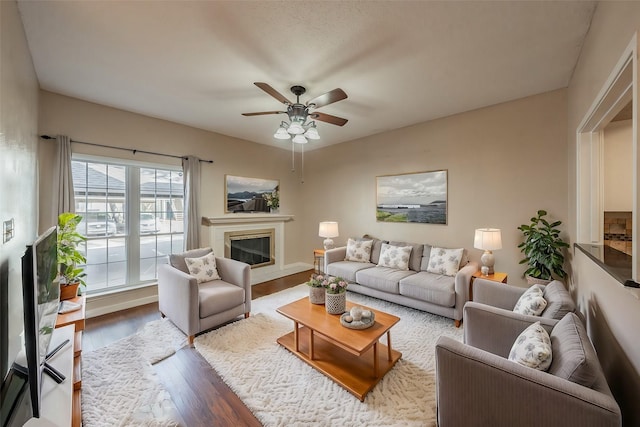 living room featuring ceiling fan, a high end fireplace, and wood-type flooring