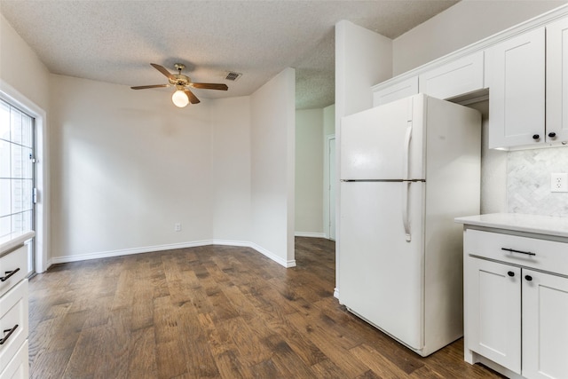 kitchen with ceiling fan, visible vents, freestanding refrigerator, dark wood-style floors, and white cabinetry