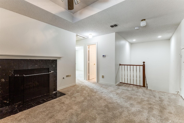 unfurnished living room featuring visible vents, a textured ceiling, carpet, and a tiled fireplace