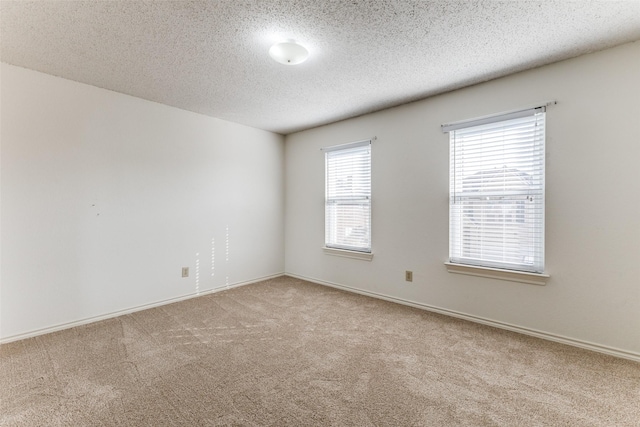 empty room with baseboards, carpet, and a textured ceiling