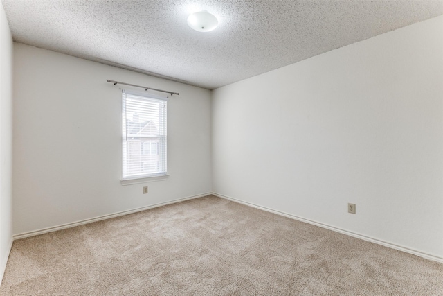 carpeted empty room featuring baseboards and a textured ceiling