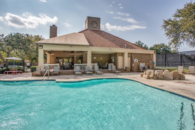 community pool with fence, a ceiling fan, and a patio area