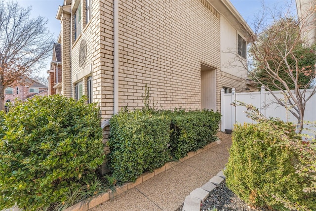 view of side of property with brick siding and fence