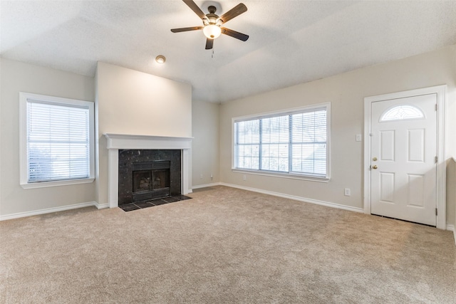 unfurnished living room with carpet flooring, ceiling fan, baseboards, and a fireplace
