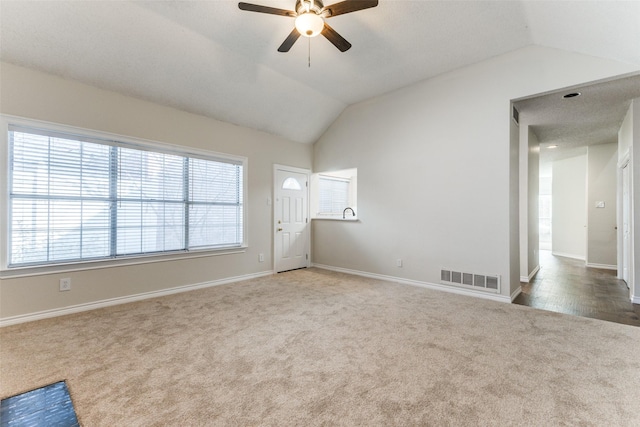 carpeted spare room featuring baseboards, ceiling fan, lofted ceiling, and visible vents