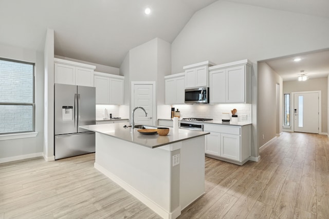 kitchen with white cabinetry, stainless steel appliances, sink, and a center island with sink