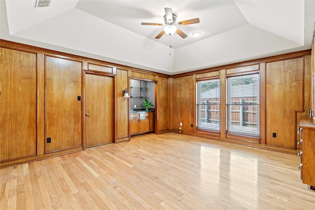 unfurnished bedroom featuring visible vents, a raised ceiling, light wood-style flooring, and lofted ceiling