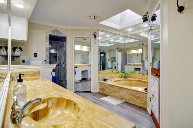 bathroom featuring ornamental molding, a skylight, a sink, and wood finished floors