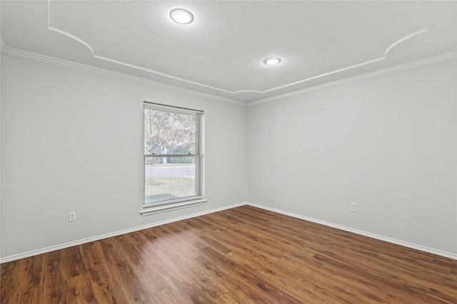 spare room featuring ornamental molding, dark wood-style flooring, and baseboards