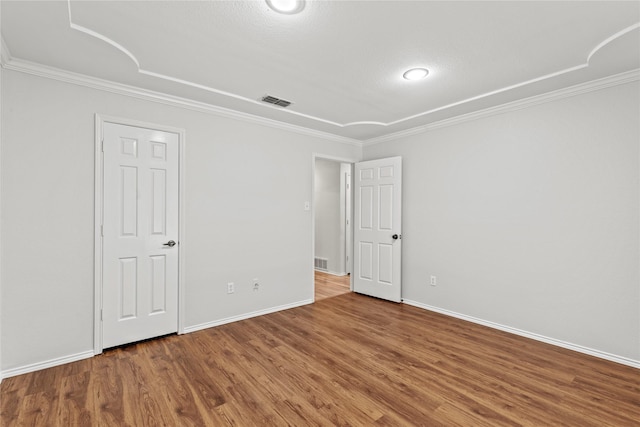 unfurnished room featuring ornamental molding, visible vents, baseboards, and wood finished floors