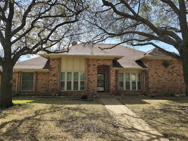 view of front of property with brick siding, board and batten siding, and a front yard