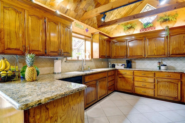 kitchen featuring lofted ceiling with beams, light stone counters, brown cabinetry, and a sink