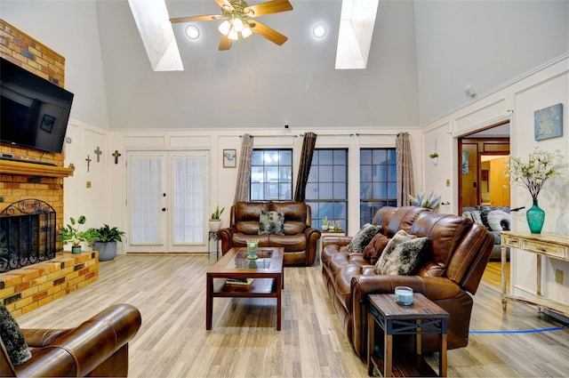 living area featuring a skylight, ceiling fan, a fireplace, and a decorative wall