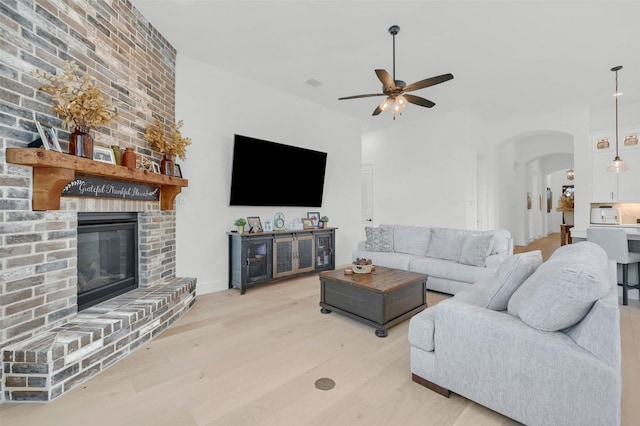 living room with ceiling fan, a fireplace, and light hardwood / wood-style floors